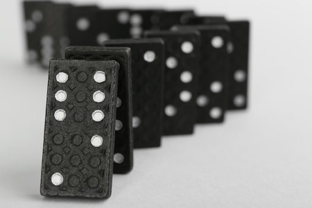 Black domino tiles falling on white background. Space for textの写真素材