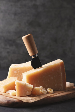 Delicious parmesan cheese with knife on black tableの写真素材