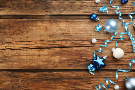 Blue serpentine streamers and Christmas baubles on wooden background, flat lay. Space for textの写真素材