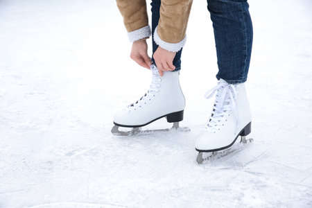 Woman lacing figure skate on ice rink, closeupの写真素材