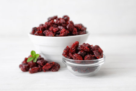 Tasty dried cranberries in bowls on white tableの写真素材