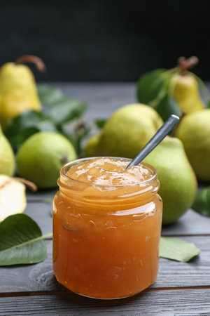 Delicious pear jam and fresh fruits on gray wooden table. Space for textの写真素材
