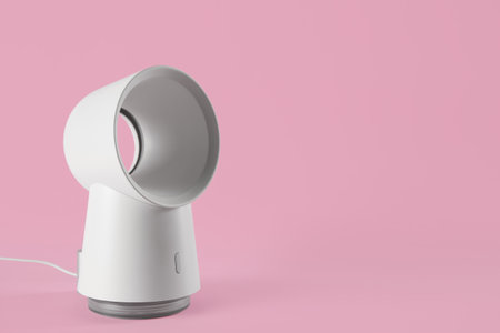 Modern electric fan on pink background. Space for textの写真素材