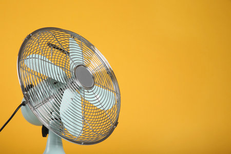 Modern electric fan on yellow background. Space for textの写真素材