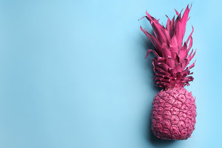 Top view of painted pink pineapple on light blue background, space for text. creative conceptの写真素材