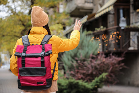Female tourist with travel backpack on city street, back view. urban tripの写真素材