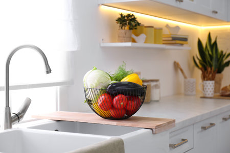 Basket full of different vegetables on wooden board in modern kitchenの写真素材