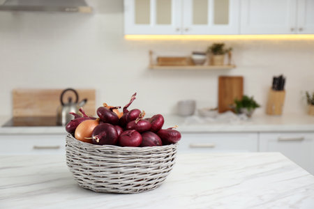 Basket with fresh onions on white marble table in modern kitchen. Space for textの写真素材