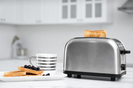 Modern toaster and tasty breakfast on white table in kitchenの写真素材