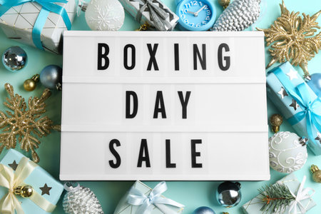 Lightbox with phrase BOXING DAY SALE and Christmas decorations on light blue background, flat layの写真素材