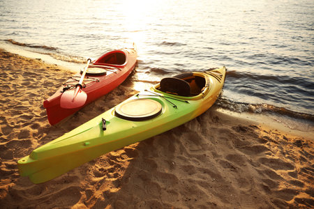 Colorful kayaks near water on river beach at sunset. summer camp activitiesの写真素材