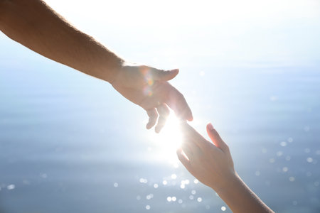 Man and woman reaching hands to each other over water, closeup. nature healing powerの写真素材