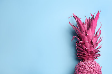 Top view of painted pink pineapple on light blue background, space for text. creative conceptの写真素材