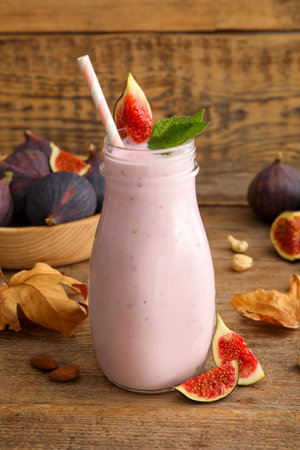 Delicious fig smoothie in glass bottle on wooden tableの写真素材