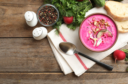 Delicious cold summer beet soup on wooden table, flat lay. Space for textの写真素材