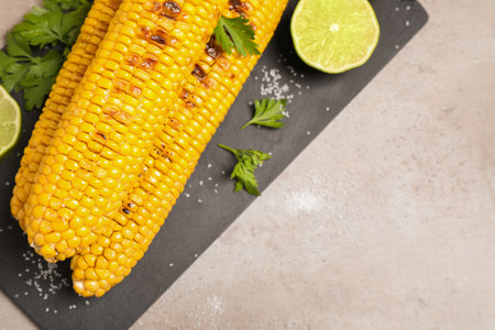 Delicious grilled corn cobs on gray table, flat lay. Space for textの写真素材