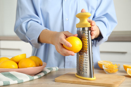 Woman zesting lemon at table indoors, closeupの写真素材