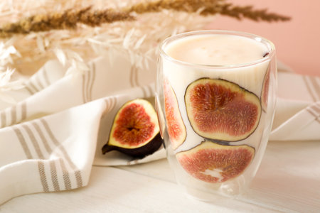 Delicious fig smoothie in glass on white wooden tableの写真素材