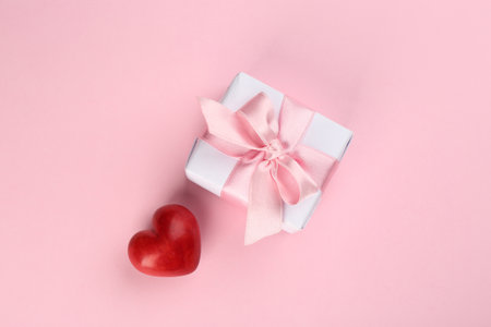 Beautiful gift box and red heart on pink background, flat lay. Valentine's day celebrationの写真素材