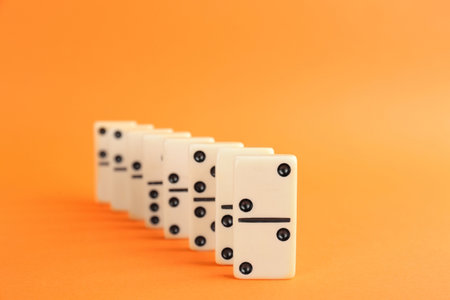 White domino tiles with black pips on orange backgroundの写真素材