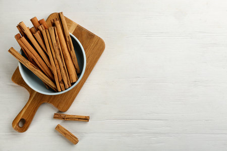 Aromatic cinnamon sticks on white wooden table, flat lay. Space for textの写真素材