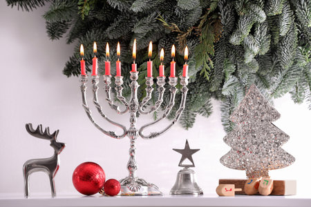 Silver menorah, Christmas decorations and dreidels with symbols He, Nun, Pe, Gimel near fir tree branches. Hanukkah symbolsの写真素材