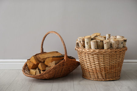 Wicker baskets with firewood near gray wall indoorsの写真素材