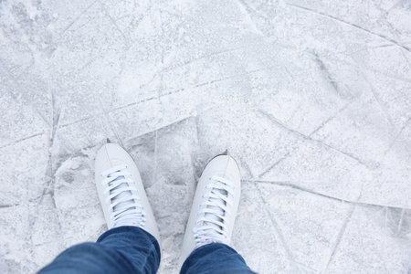 Woman wearing figure skates on ice rink, top view. Space for text