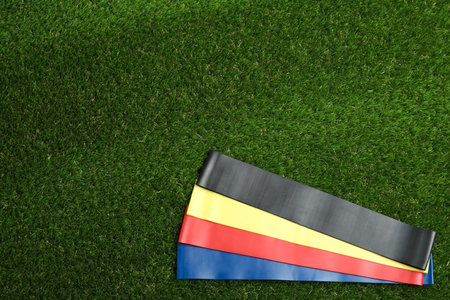 Fitness elastic bands on green grass, flat lay. Space for textの写真素材