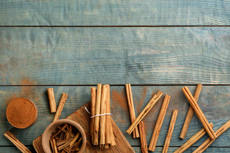 Aromatic cinnamon sticks and powder on light blue wooden table, flat lay. Space for textの写真素材