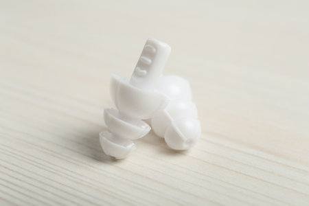 Pair of ear plugs on white wooden background, closeup