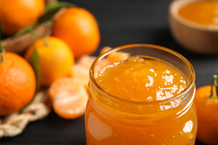 Tasty tangerine jam in glass jar on table, closeup. Space for textの写真素材