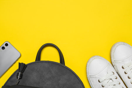 Stylish casual backpack, smartphone and sneakers on yellow background, flat lay. Space for textの写真素材