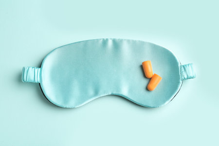 Pair of ear plugs and sleeping mask on turquoise background, flat layの写真素材