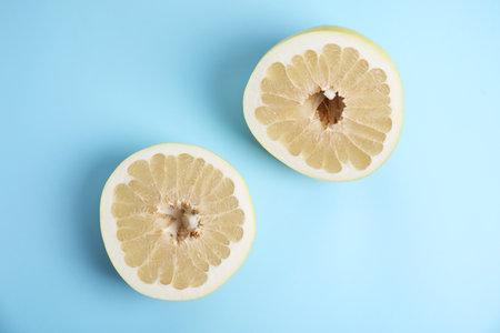Fresh cut pomelo fruit on light blue background, flat layの写真素材