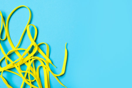 Yellow shoelaces on light blue background, flat lay. Space for textの写真素材