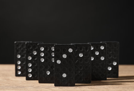 Domino tiles on wooden table against black background. Space for textの写真素材
