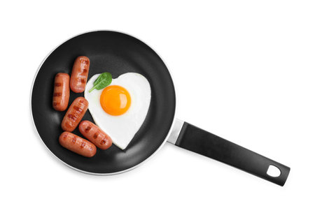 Romantic breakfast with fried sausages and heart shaped egg isolated on white, top view. Valentine's day celebrationの写真素材