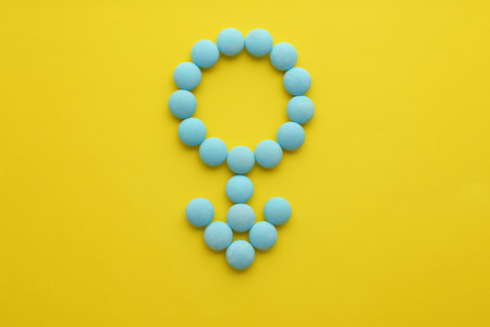 Male sign made of blue pills on yellow background, flat lay. Potency problemsの写真素材