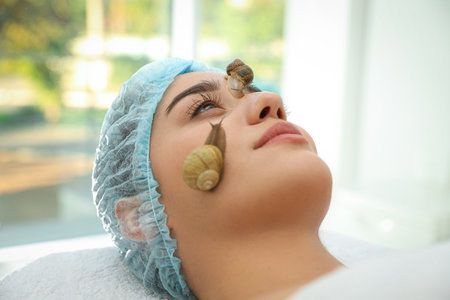 Young woman receiving snail facial massage in spa salon, closeupの写真素材