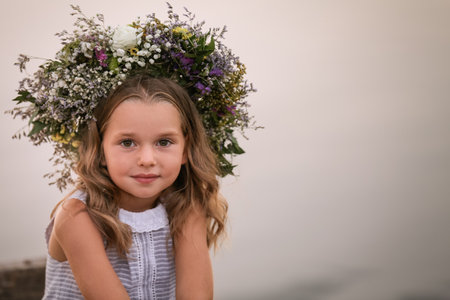 Cute little girl wearing wreath made of beautiful flowers on blurred backgroundの写真素材