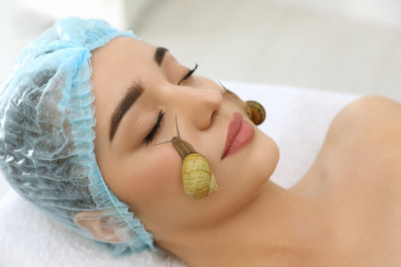 Young woman receiving snail facial massage in spa salon, closeupの写真素材