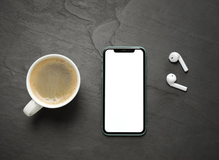 MYKOLAIV, UKRAINE - JULY 8, 2020: Iphone 11 Pro Max with blank screen, cup of coffee and earphones on black background, flat layのeditorial素材