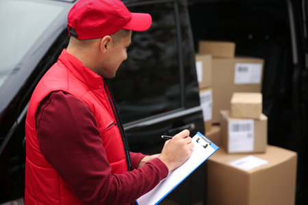 Courier checking amount of parcels in delivery van outdoors. Space for textの写真素材