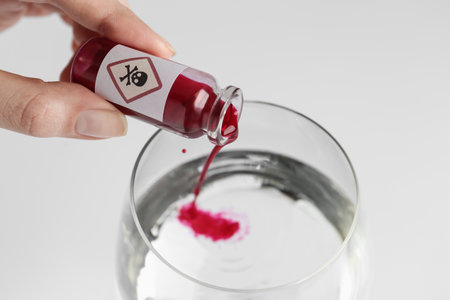Woman pouring poison into glass of water on white background, closeupの写真素材
