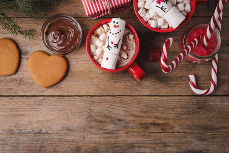 Flat lay composition with marshmallow snowmen on wooden table. Space for text