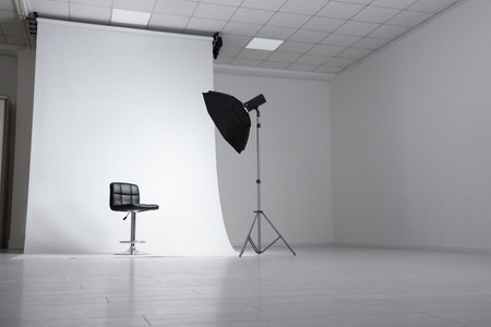 Photo studio interior with modern chair and professional lighting equipmentの写真素材