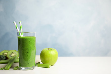 Delicious green juice and fresh ingredients on white table against light blue background, space for textの写真素材