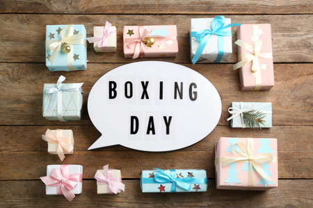 Flat lay composition with Boxing Day sign and Christmas gifts on wooden tableの写真素材