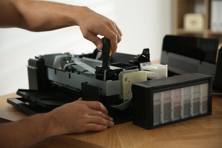 Repairman with screwdriver fixing modern printer, closeupの写真素材